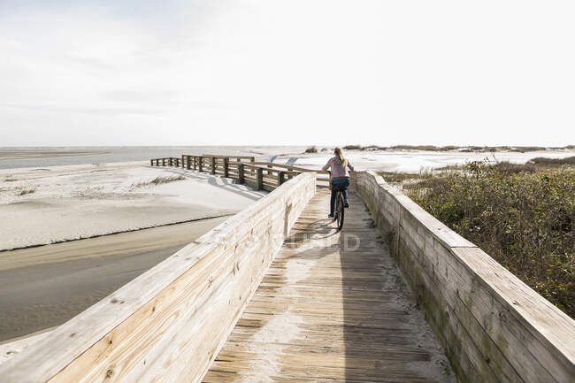 Adolescent fille sur son vélo traversant pont à la plage, St. Simon Island, Géorgie — Photo de stock