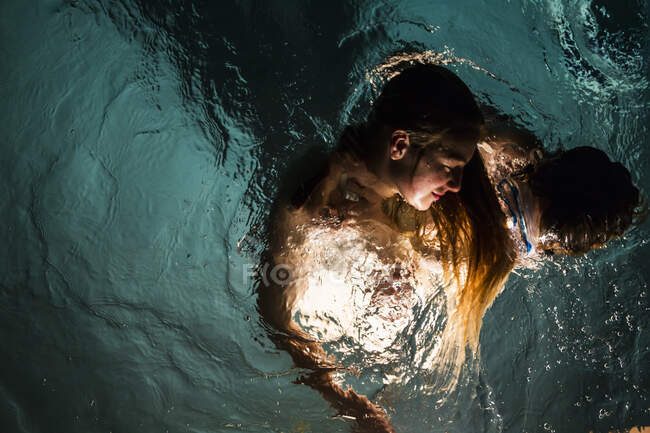 Zwei Kinder schwimmen nachts im Pool — Stockfoto
