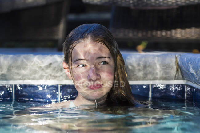 13-летняя девочка в бассейне, на лице которой играет Мбаппе — стоковое фото