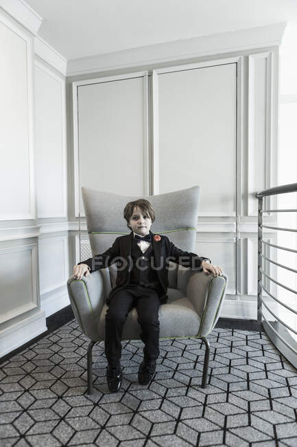 Portrait d'un garçon de 6 ans assis sur une chaise — Photo de stock