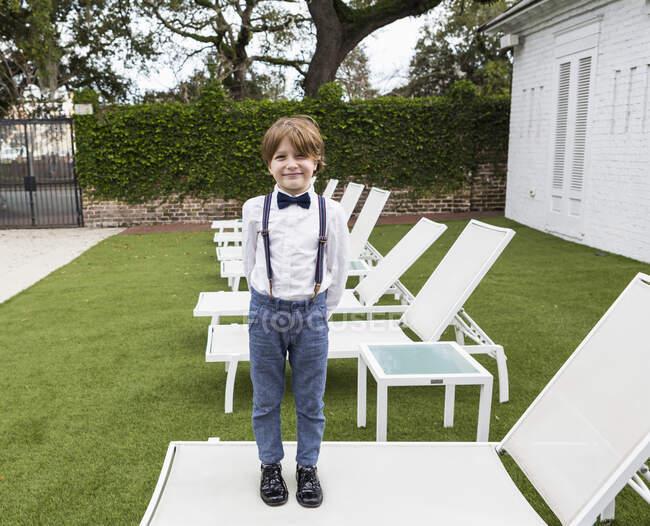 6 anno vecchio ragazzo standing su prato sedia — Foto stock