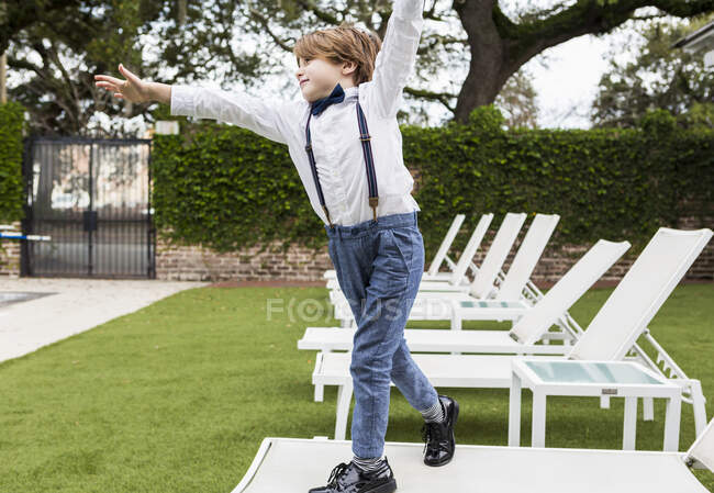 Garçon de 6 ans debout sur une chaise de pelouse — Photo de stock