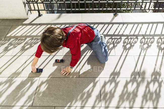 6-jähriger Junge spielt mit Spielzeugautos auf Terrasse — Stockfoto