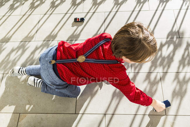 Garoto de 6 anos brincando com carros de brinquedo no terraço — Fotografia de Stock