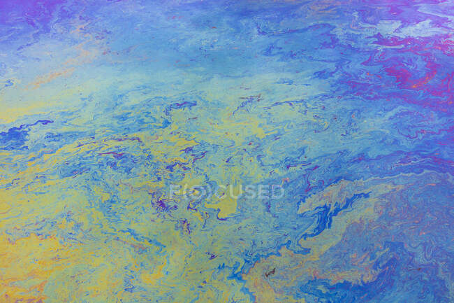 Spilled diesel fuel on surface on ocean water, close up, blue and yellow pattern — Stock Photo