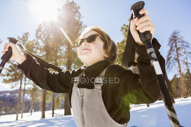 Шестилетний мальчик в лесу держит лыжные палки — стоковое фото