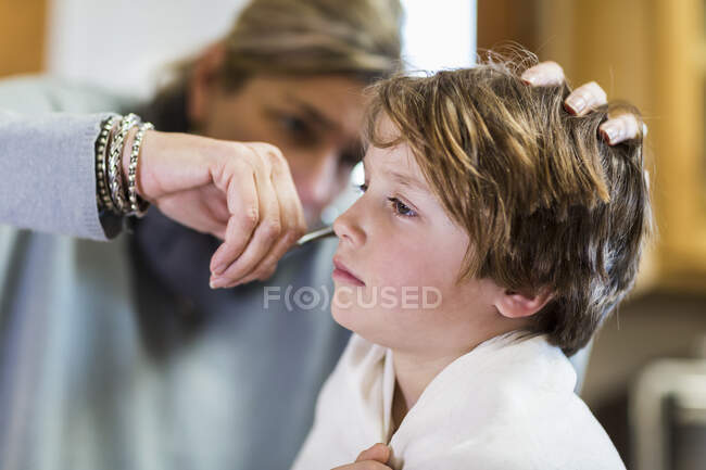 Мати ріже волосся до чарівного сина вдома — стокове фото