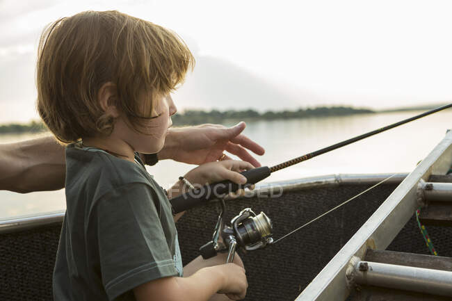Um menino de cinco anos pescando de um barco no rio Zambeze, Botsuana — Fotografia de Stock