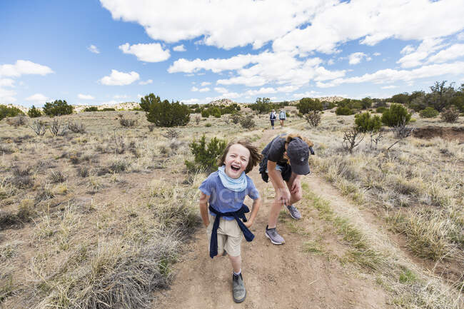 Six year old boy running on hiking trail with older sister, Galisteo Basin, NM. — Fotografia de Stock