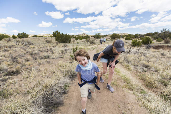 Ragazzo di 6 anni che corre sul sentiero escursionistico con la sorella maggiore, bacino del Galisteo, NM. — Foto stock