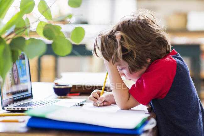 Uma criança trabalhando em casa, escrevendo em um caderno, escola em casa, durante um confinamento — Fotografia de Stock