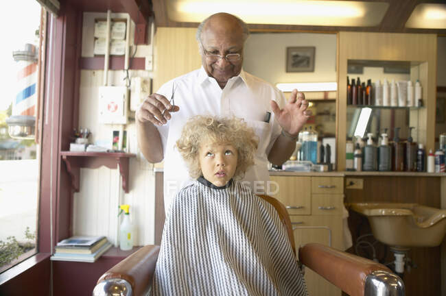 Barber examining young boy wild hair — Stock Photo