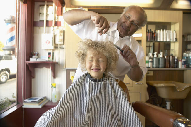 Jeune garçon pleurant tandis que le coiffeur se coupe les cheveux — Photo de stock