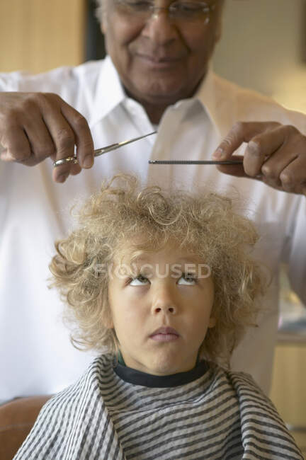 Barber carefully cutting young boy hair — Stock Photo