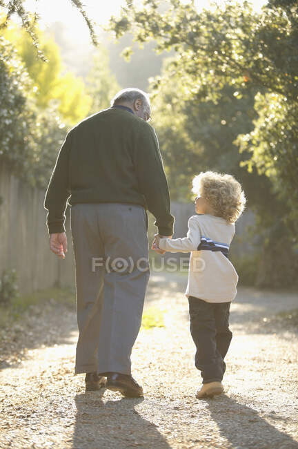 Hombre mayor caminando con su nieto - foto de stock