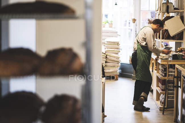 Artisan bakery making special sourdough bread, racks of bread and a baker in the background. — Stock Photo