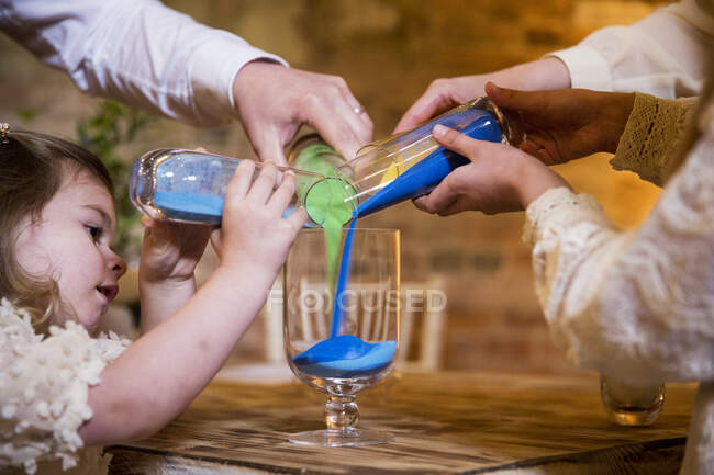 Família derramando areia colorida em frasco de vidro durante a cerimônia de nomeação em um celeiro histórico. — Fotografia de Stock