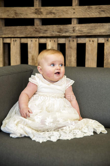 Portrait of baby girl in white gown during naming ceremony in an historic barn. — Stock Photo