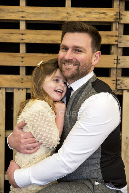Portrait of bearded man hugging his young daughter during naming ceremony in an historic barn. — Stock Photo