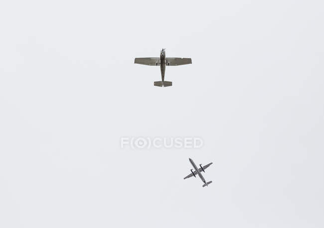 The underside of two aeroplanes flying in a grey sky. — Stock Photo