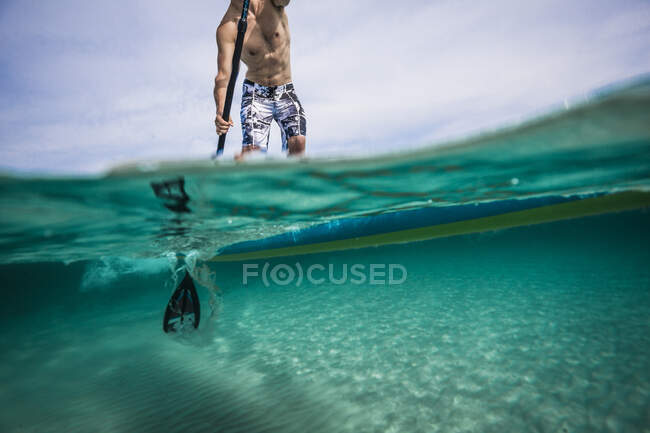 Person on a paddleboard both underwater and above the surface. — Stock Photo