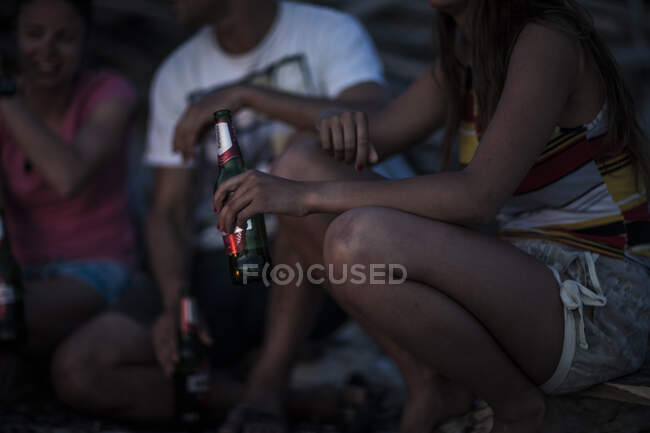 Группа молодых людей собралась на пляже и пила пиво. — стоковое фото