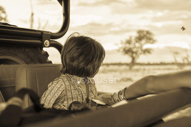 Um menino de cinco anos em safari, em um veículo em uma reserva de caça. — Fotografia de Stock