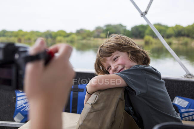 Un niño de cinco años sonriendo a la cámara en un barco fluvial en el río Zambezi. - foto de stock