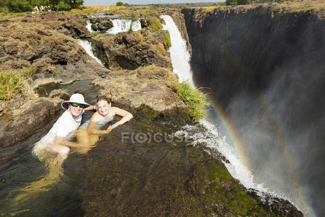 Maturo uomo e ragazza, padre e giovane figlia adolescente in acqua presso la piscina Devils, sulla scogliera che domina Victoria Falls, Zambia — Foto stock