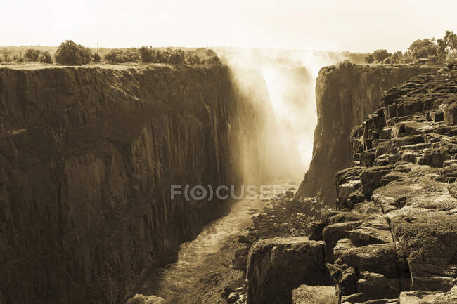 Victoria Falls from the Zambian side, deep river gorge with vertical sides and mist from tumbling water. — Stock Photo