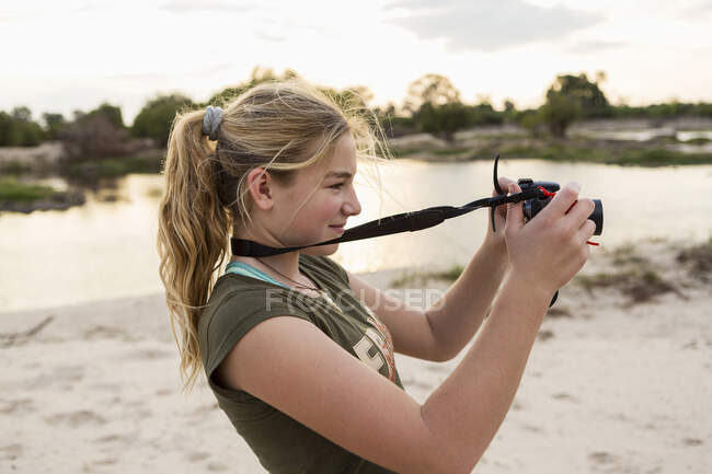 Одна дванадцятирічна дівчинка фотографується у відпустці в Ботсвані на заході сонця, на березі річки Замбезі.. — стокове фото