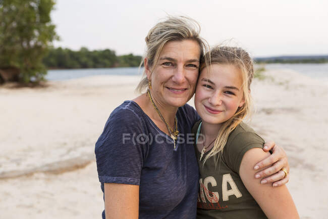 Зрелая женщина и молодая девочка-подросток, мать и дочь на берегу широкой реки. — стоковое фото