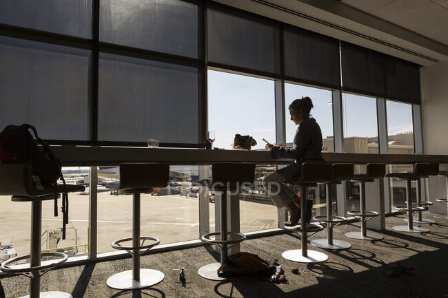 Uma mulher madura, executiva feminina sentado usando um laptop em um salão de embarque do aeroporto — Fotografia de Stock