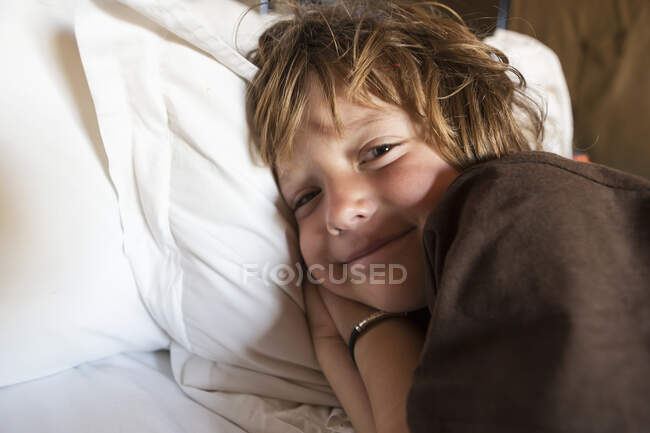 Um menino sorridente de 5 anos na cama em sua tenda, deserto de Kalahari. — Fotografia de Stock