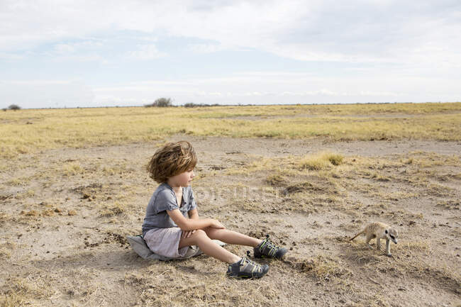 Niño de 5 años mirando Meerkat, desierto de Kalahari, sartenes Makgadikgadi, Botswana - foto de stock