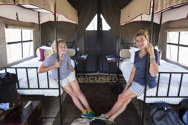 Unterkunft in einem Wildlife Reserve Camp, Mutter und Tochter sitzen auf Betten in einem Zelt. — Stockfoto