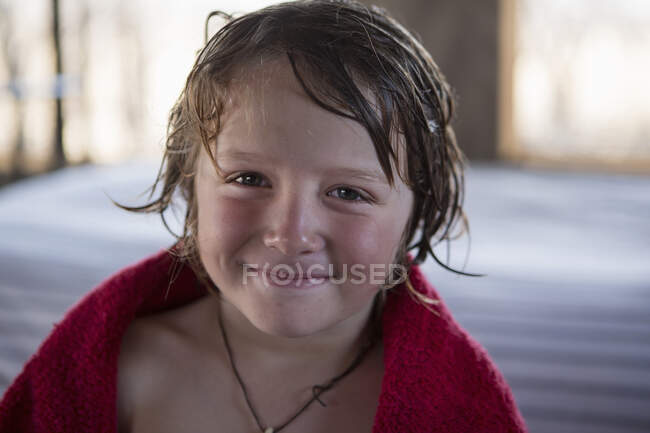 Um menino de cinco anos com cabelo molhado e uma toalha vermelha, sorrindo. — Fotografia de Stock