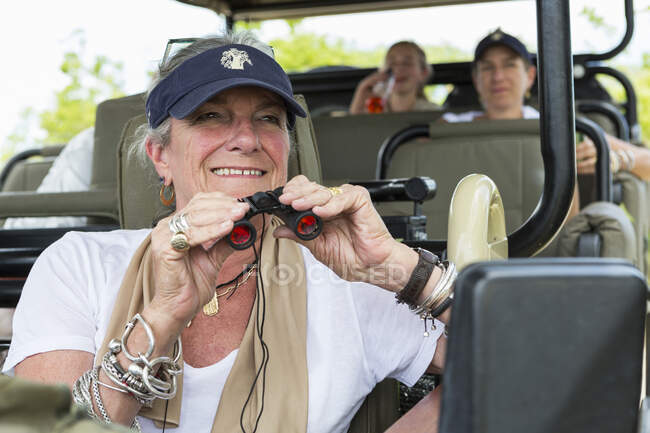 Familie im Safarifahrzeug in einem Wildtierreservat, eine Seniorin mit Fernglas. — Stockfoto