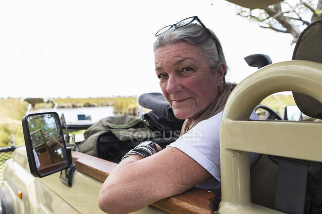 Eine Seniorin auf dem Beifahrersitz eines Safarifahrzeugs in einem Naturschutzgebiet. — Stockfoto