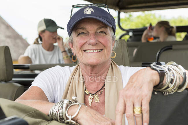 A family in a safari vehicle in a wildlife reserve, a mature woman and two passengers behind. — Stock Photo