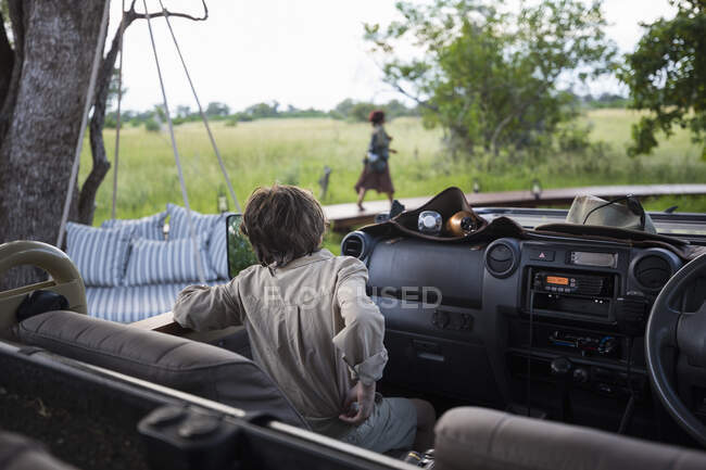 Un niño de seis años en el asiento delantero de un vehículo de safari - foto de stock