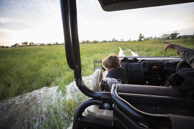 Ein sechsjähriger Junge, der in einem Safari-Fahrzeug mit Blick über die Landschaft reitet — Stockfoto