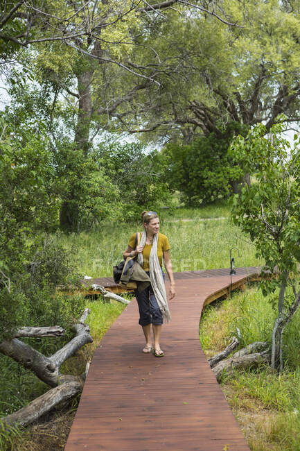 Adult woman walking wooden path, tented camp, Botswana — Stock Photo