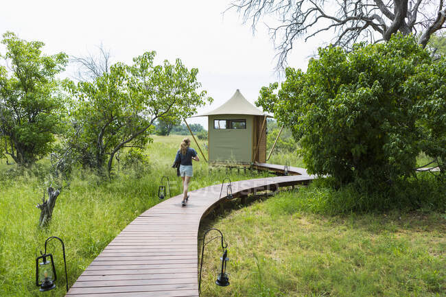 13 year old girl walking wooden path, tented camp, Botswana — Stock Photo
