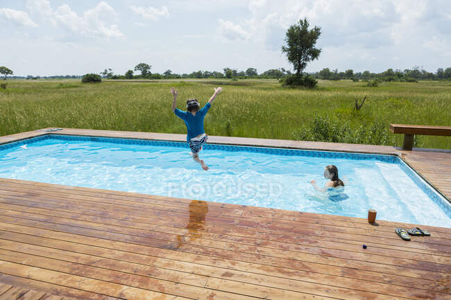 Garçon de 6 ans sautant dans la piscine, camp de tentes, Botswana — Photo de stock