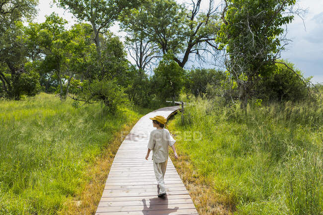 6 year old boy walking on wooden walkway in a safari camp. — Stock Photo