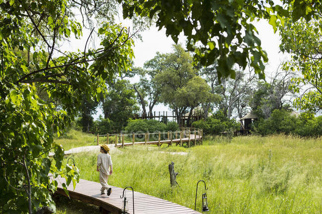 6-jähriger Junge läuft auf Holzsteg in Safaricamp. — Stockfoto
