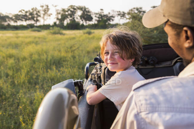 Sorrindo 6 anos de idade menino direção safari veículo, Botswana — Fotografia de Stock