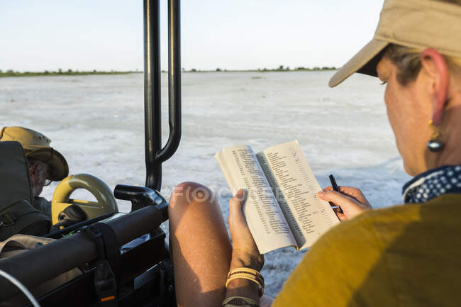 Mulher olhando para um livro ou diário em um veículo de safári, Botsuana — Fotografia de Stock