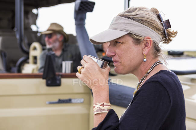 Mujer adulta bebiendo café en safari, Nxai Pan, Botswana - foto de stock